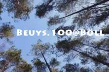 Schriftzug "BEUYS.100@BöLL", blauer Himmel und Baumkronen 