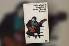 Das Buchcover von "Ansichten eines Clowns" von Heinrich Böll zeigt einen illustrierten Menschen, der sitzend Gitarre spielt und den Kopf zur Seite neigt.