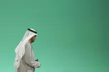 Der Leiter der COP28, Sultan Al Jaber, steht allein vor einer grün-trürkisfarbenen Wand. Er ist von der Seite zu sehen und wirkt müde.