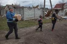 Eine Frau und zwei Kinder laufen durch Novoselivka, ein zerstörtes Dorf in der Ukraine.