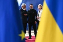 EU-Sondergipfel am 6. März 2025 Foto: Drei Personen stehen auf einem roten Teppich, umgeben von EU- und Ukraine-Fahnen. Links António Costa, Präsident des Europäischen Rates, in der Mitte der ukrainische Präsident Volodymyr Zelenskyy, rechts EU-Kommissionspräsidentin Ursula von der Leyen.