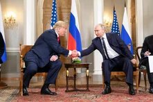 US President Donald J. Trump and President Vladimir Putin of the Russian Federation Donald Trump and Vladimir Putin sit facing each other and shake hands. A small table with flowers is between them.