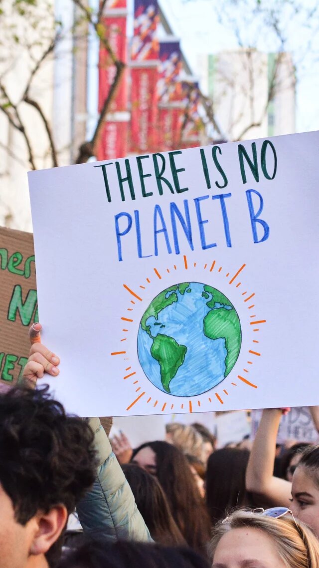 Klimademonstration ine Menschenmenge bei einer Klima-Demonstration. Ein großes Schild zeigt eine Erde mit dem Text „There is no Planet B“. („Es gibt keinen Planet B“)