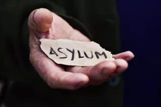 Offene Hand in der ein abgerissener Zettel liegt, auf dem Asylum steht