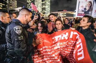 Tel Aviv, Israel: Israelische Polizeibeamte schieben weibliche Demonstrant*innen mit Plakat weg, die die Straße blockieren