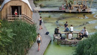 Viele Menschen sitzen auf Bänke im Wasser beim Floating University. Es gibt auch eine Hütte und einen Laufweg über das Wasser