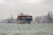 Ein mit Containern beladenes Schiff verlässt einen Hafen