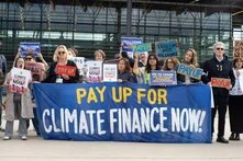 Demonstrierende mit einem Banner mit der Aufschrift: Pay Up For Climate Finance Now!