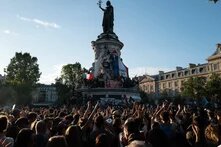 Foto: Paris, Place de la République. Eine Menschenmenge feiert nach der Wahl am 7. Juli 2024. Einige halten Fahnen und Transparente.