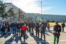 Foto: Eine Gruppe serbischer Polizist*innen steht einer Menge von Demonstrierenden gegenüber. Im Hintergrund ist ein großes, rechteckiges Gebäude.