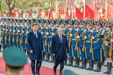 Foto: Xi Jinping und Luiz Inácio Lula da Silva schreiten eine Ehrengarde entlang. Chinesische Soldat*innen stehen in Reihen mit Gewehren und roten Fahnen im Hintergrund.