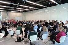 Frühjahrstagung 2025 der Grünen Akademie Über 50 Personen sitzen im Stuhlkreis in einem modernen Raum und hören einer Diskussion zu. Zwei Personen sprechen mit Mikrofon.