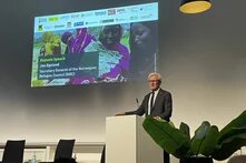 Jan Egeland auf der Konferenz "Sudan – Thinking Peace and humanitarian Protection from a civilian perspective" Ein Mann spricht an einem Rednerpult vor Leinwand mit Ankündigung: „Keynote Speech Jan Egeland, Norwegian Refugee Council (NRC)“.