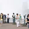 Menschen auf einem Aussichtspunkt, dahinter Smog