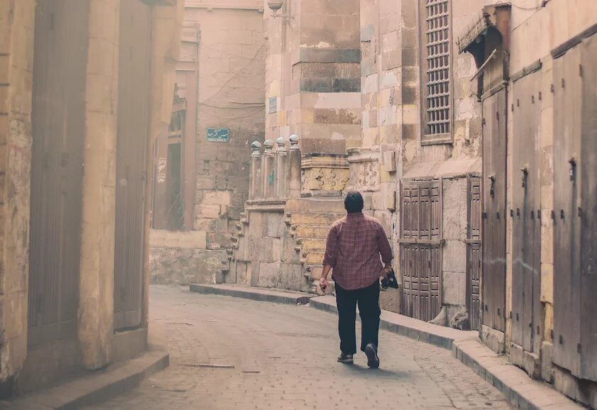 Man walks down a narrow empty street in Cairo, Egypt. 