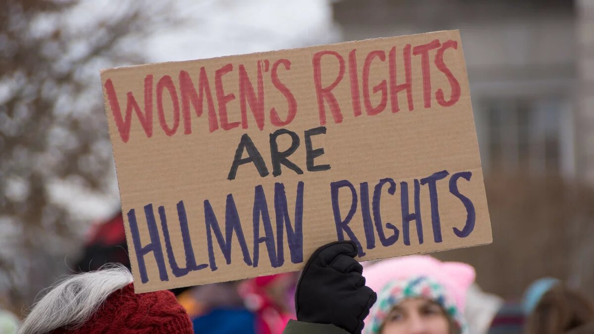 Auf einer Demonstration hält jemand ein Schild hoch mit der Aufschrift "Women's Rights Are Human Rights"