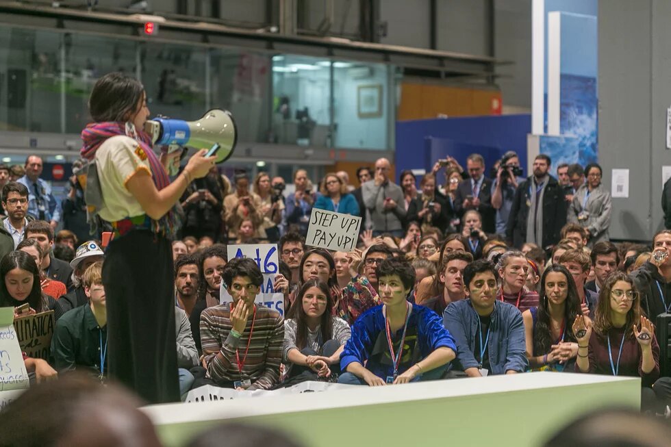 A girl speaking at COP25 in front of many young people 