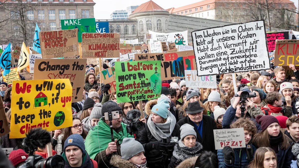 Junge Menschen demonstrieren mit Schilden und Plakaten für mehr Klimaschutz