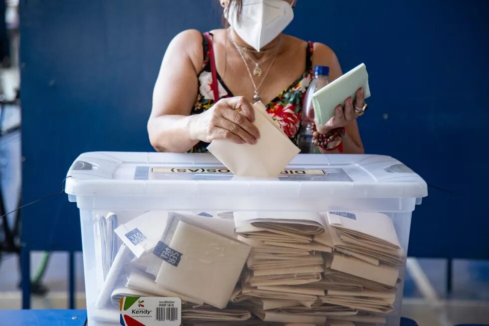 Eine Frau wirft Wahlumschläge in eine Kiste