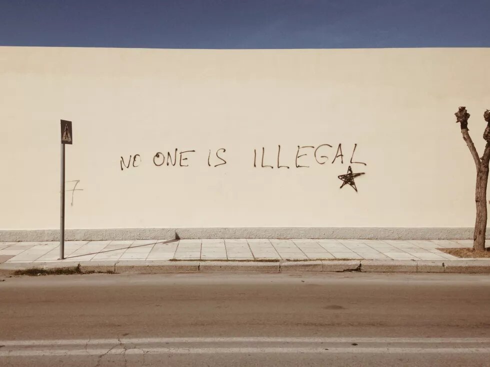 Eine Wand ist mit dem Satz "No one is illegal" beschriftet