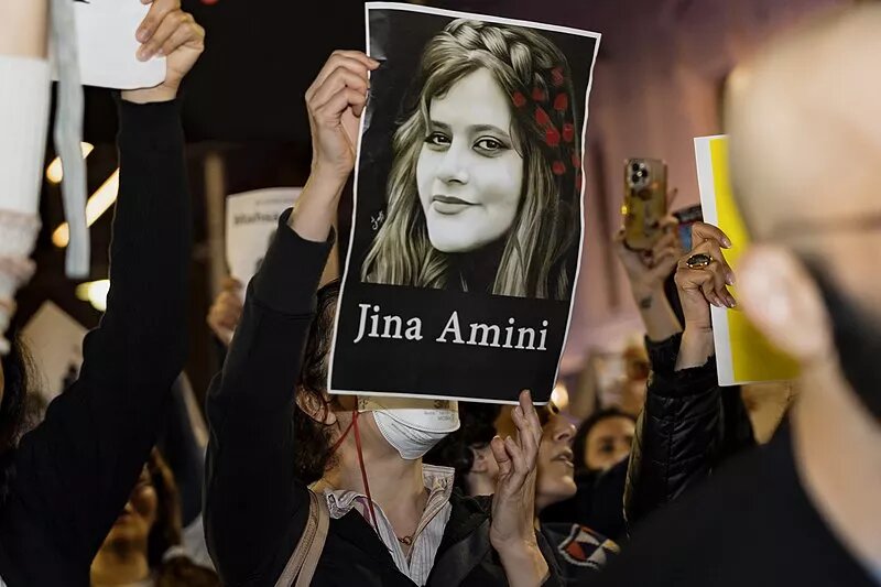 Eine Demonstrantin hält ein Bild von Jina Amini hoch