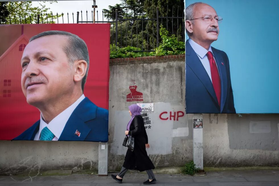 Eine Person läuft an zwei Wahlplakaten vorbei, das eine Plakat zeigt das Porträt von Recep Tayyip Erdoğan, das andere das Porträt von Kemal Kılıçdaroğlu