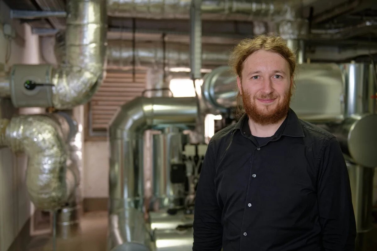 Raphael Gruseck im Hintergrund die silbernen Rohre Heizungsanlage