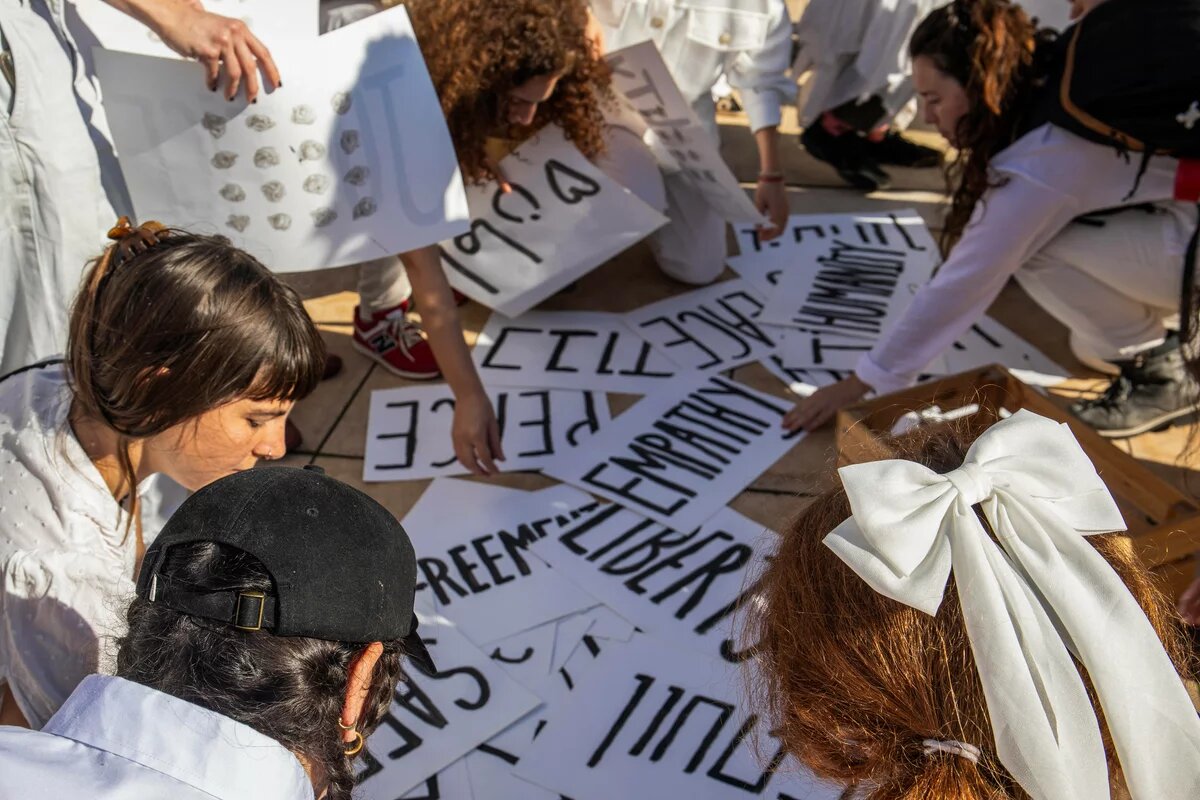 Jüdisch-israelische Frauen und palästinensische Frauen bei einer Friedensperfomance am 15. Dezember 2023 in Tel Aviv mit verschiedenen Schildern, die für Ideale wie Gerechtigkeit, Respekt, Freiheit, Menschlichkeit und mehr warben.