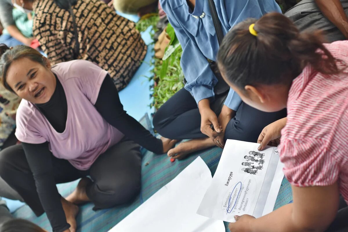 Several women are discussing while sitting in a circle on the floor 