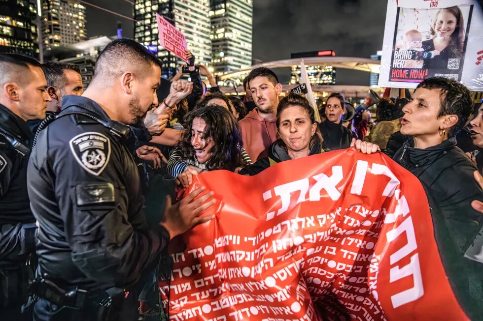 Tel Aviv, Israel: Israelische Polizeibeamte schieben weibliche Demonstrant*innen mit Plakat weg, die die Straße blockieren