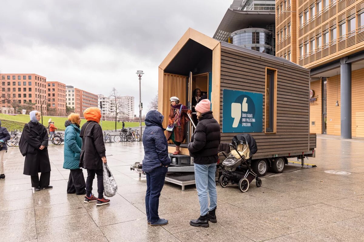 ​ winziges Haus auf Rädern mit spitzem Dach, Holzverkleidung und einer kleinen Veranda Safer Space am Potsdamer Platz