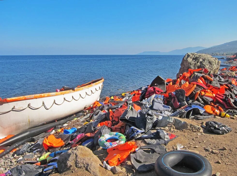 Flüchtlingsboot am Meeresufer und unzählige Schwimmwesten am Strand