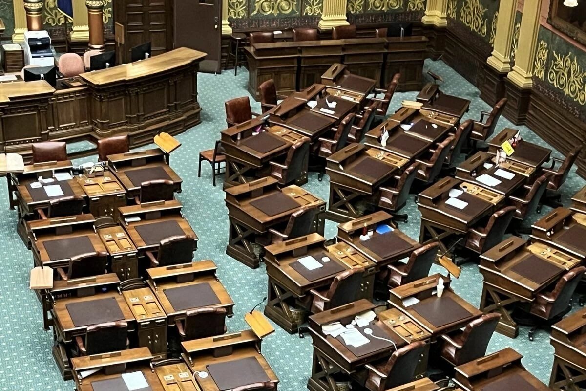 Foto: Der leere Sitzungssaal im Michigan State House mit hölzernen Schreibtischen und Ledersesseln, angeordnet in Reihen.