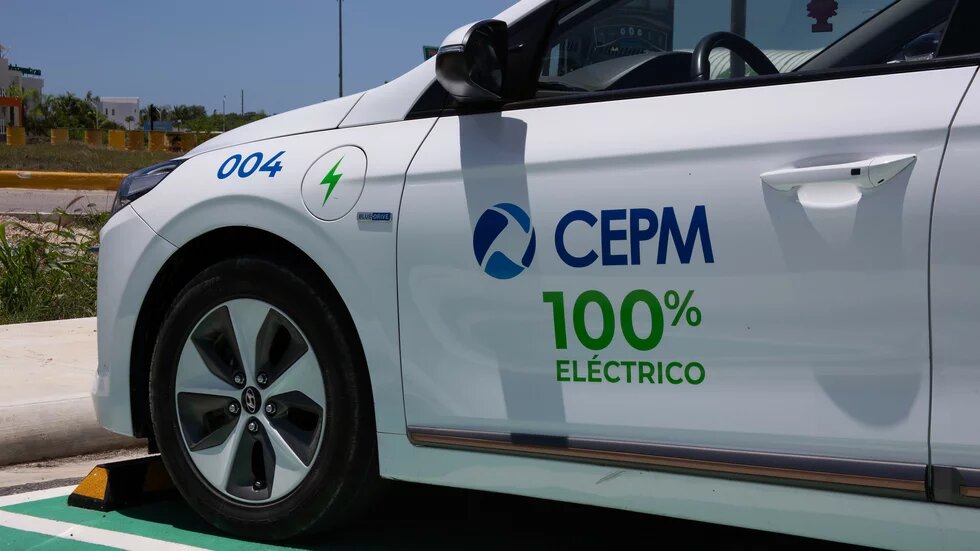 Foto: Seitenansicht eines Elektroautos mit CEPM-Logo und der Aufschrift "100% Eléctrico". Das Auto steht auf einem Parkplatz, im Hintergrund sind Gebäude.