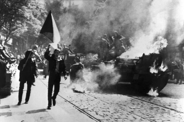 Einwohner von Prag mit tschechoslowakischer Flagge vor einem zerstörten sowjetischen Panzer