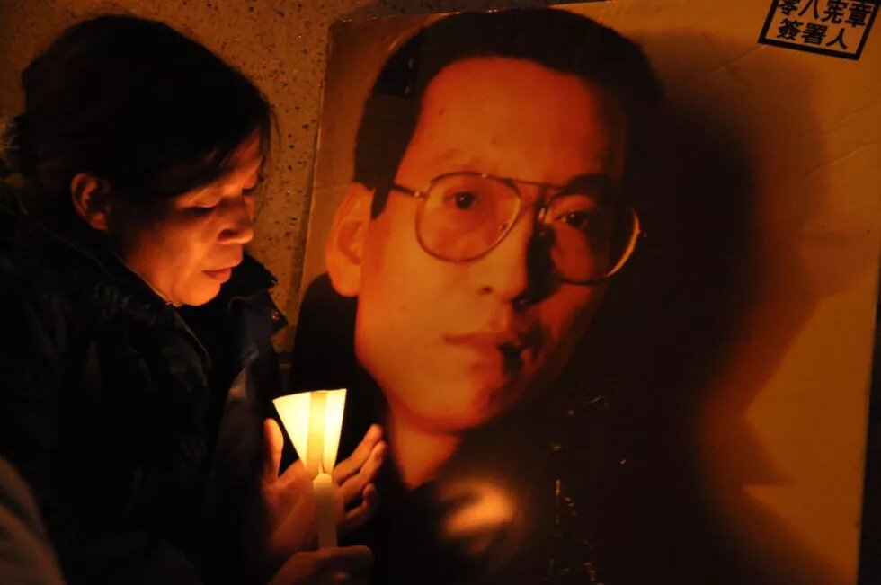 Eine Frau mit einer Kerze vor einem Bild von Liu Xiaobo