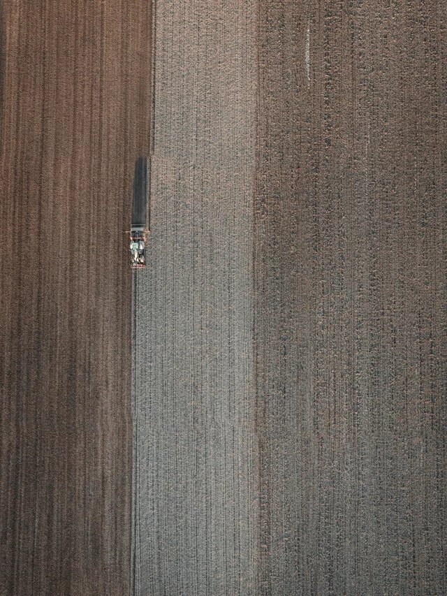 Luftaufnahme eines Ackers, der von einem Pflug bearbeitet wird.