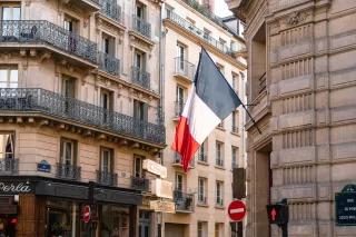 Französische Nationalfahne an einem Gebäude über einer roten Ampel